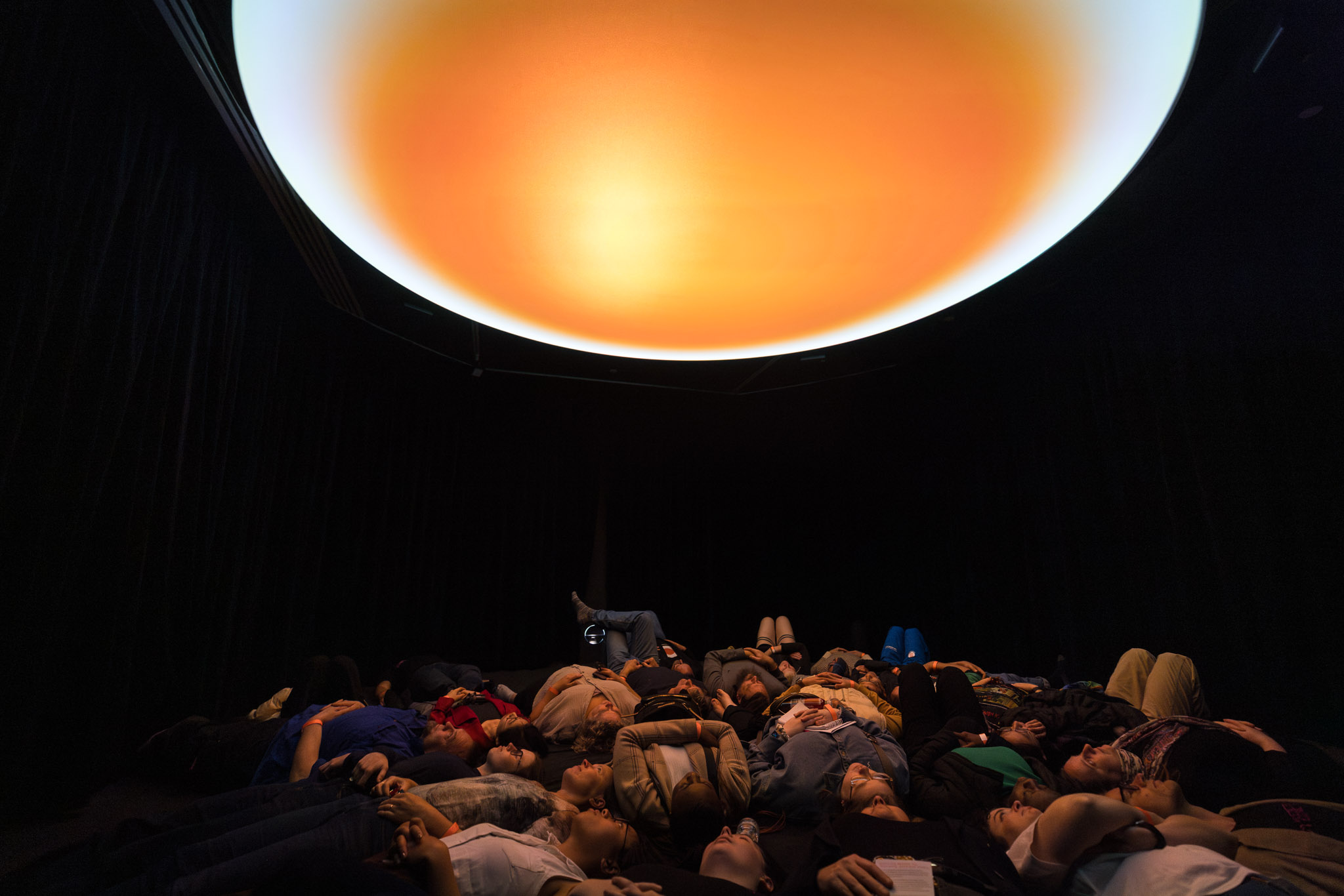 People lying down under an orange projection
